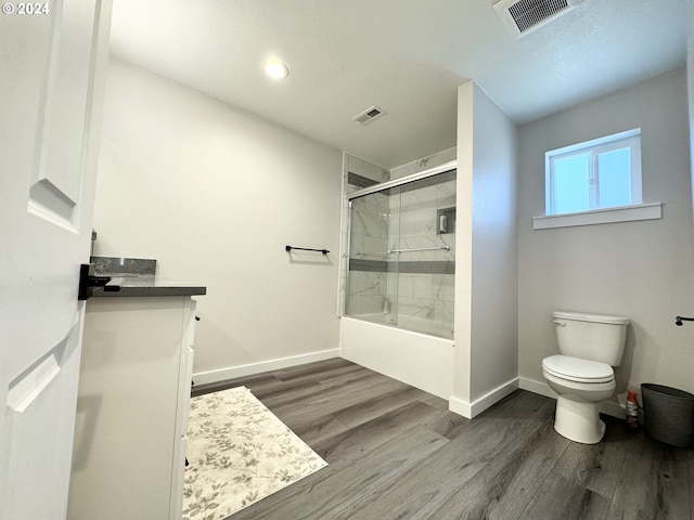 full bathroom with vanity, toilet, shower / bath combination with glass door, and wood-type flooring