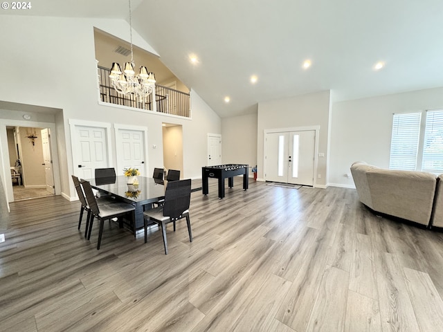 dining space featuring light hardwood / wood-style floors, a chandelier, high vaulted ceiling, and french doors