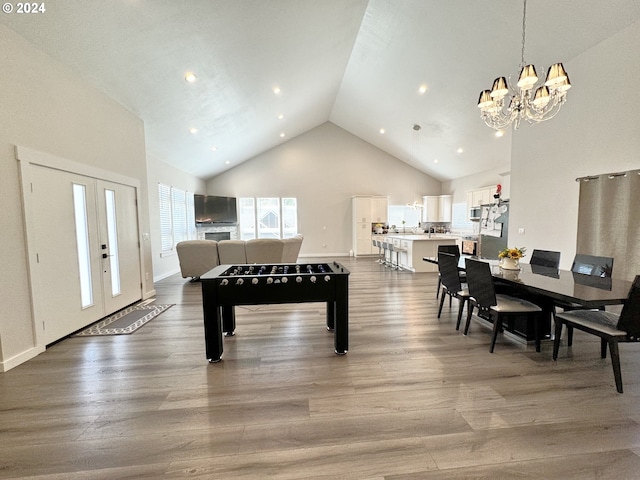 playroom with wood-type flooring, a chandelier, high vaulted ceiling, and french doors