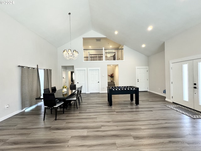 dining space with hardwood / wood-style floors, an inviting chandelier, a towering ceiling, and french doors