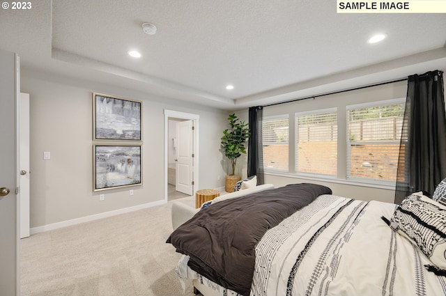 bedroom featuring light carpet, a textured ceiling, and ensuite bath