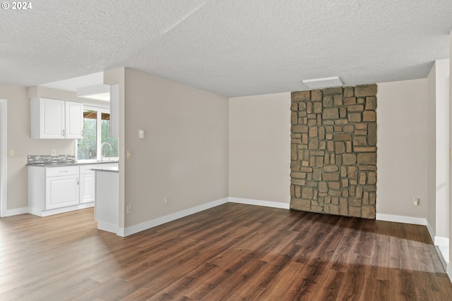 unfurnished living room featuring dark hardwood / wood-style flooring, a textured ceiling, and sink