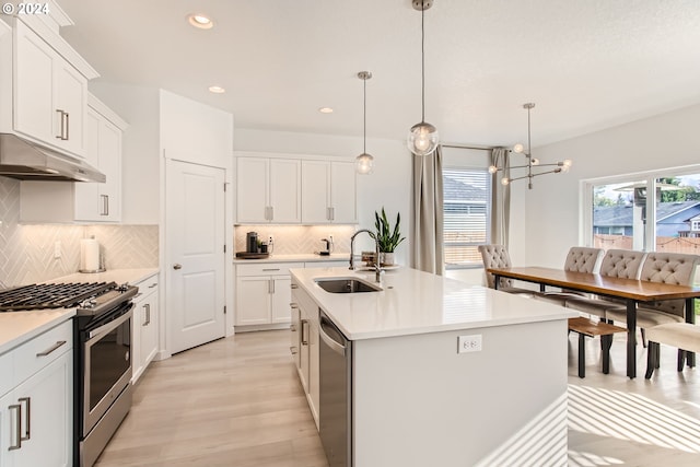 kitchen with pendant lighting, white cabinetry, sink, a kitchen island with sink, and stainless steel appliances