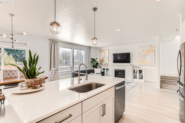 kitchen featuring dishwasher, sink, white cabinets, hanging light fixtures, and a textured ceiling