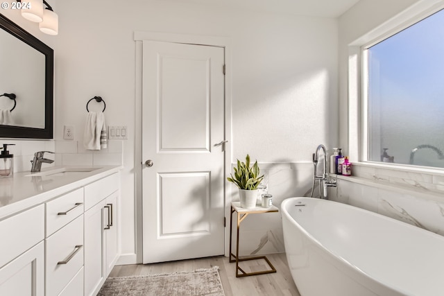 bathroom featuring a healthy amount of sunlight, hardwood / wood-style floors, vanity, and a tub