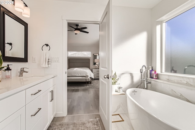 bathroom featuring a washtub, vanity, hardwood / wood-style floors, and ceiling fan