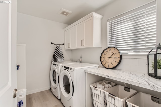 clothes washing area with cabinets, independent washer and dryer, and light hardwood / wood-style floors