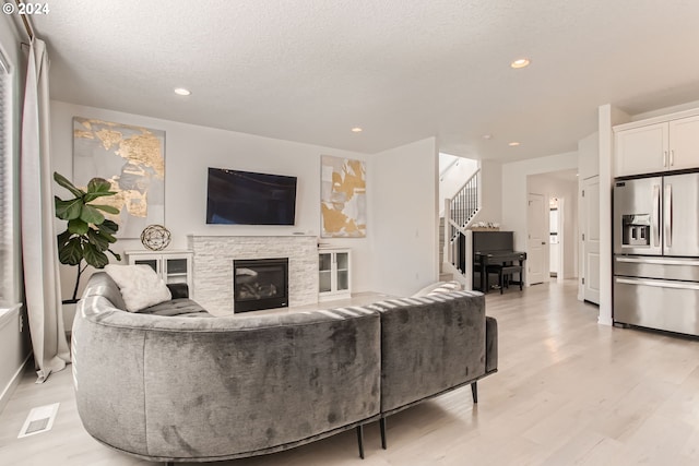 living room featuring a fireplace, light hardwood / wood-style flooring, and a textured ceiling