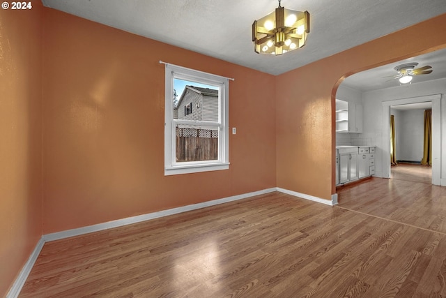 unfurnished room featuring hardwood / wood-style floors, ceiling fan with notable chandelier, and a textured ceiling