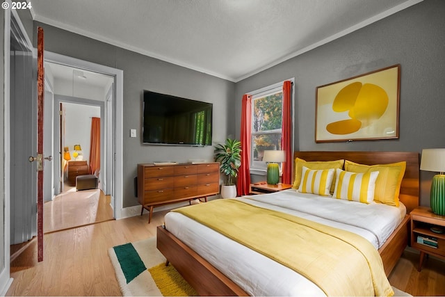 bedroom with light hardwood / wood-style flooring, a textured ceiling, and ornamental molding