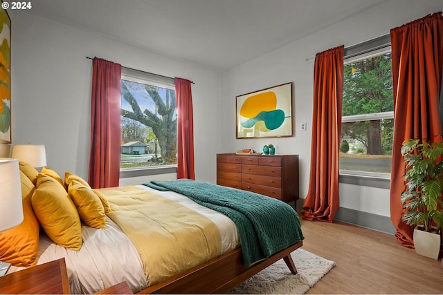 bedroom with multiple windows and light hardwood / wood-style flooring