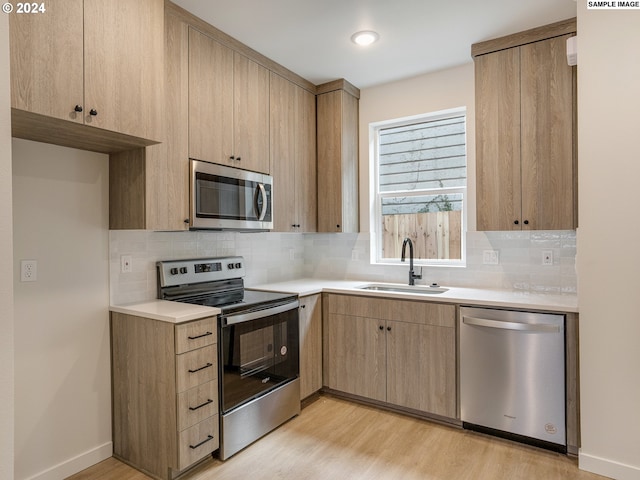 kitchen with tasteful backsplash, stainless steel appliances, light hardwood / wood-style floors, light brown cabinets, and sink