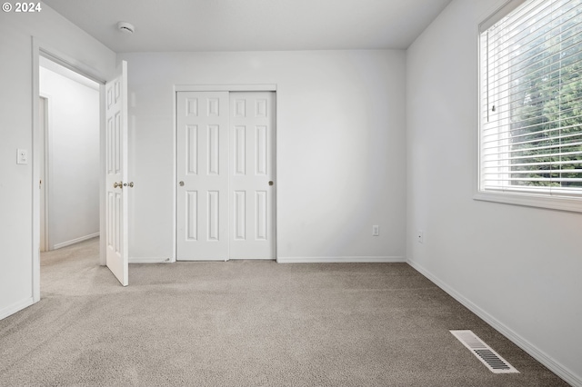 unfurnished bedroom with a closet, light carpet, and multiple windows