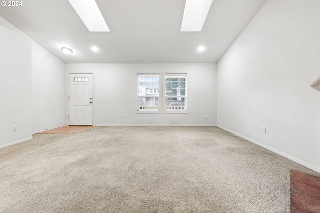 unfurnished living room with lofted ceiling with skylight and carpet