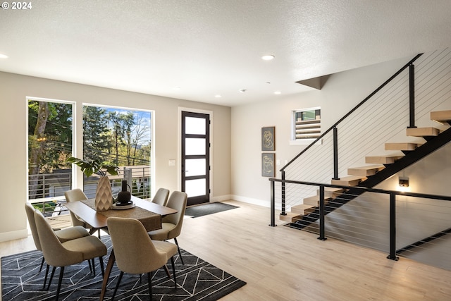 dining area with light wood-type flooring and a textured ceiling