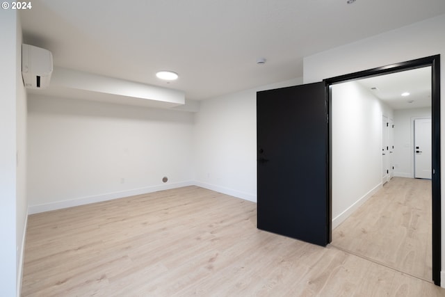 unfurnished room featuring a wall mounted AC and light wood-type flooring