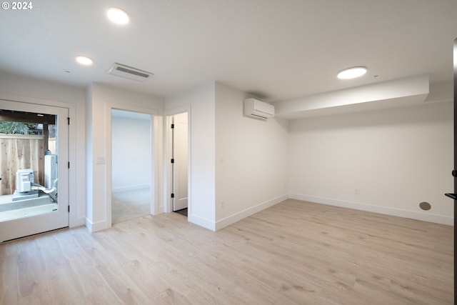 unfurnished room with a wall mounted air conditioner and light hardwood / wood-style flooring