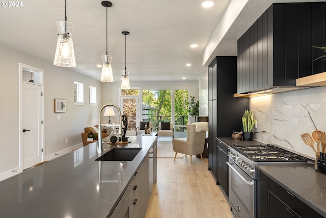 kitchen with stainless steel stove, sink, light hardwood / wood-style floors, and pendant lighting