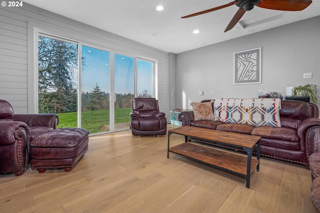 living room with ceiling fan, light hardwood / wood-style floors, and wood walls