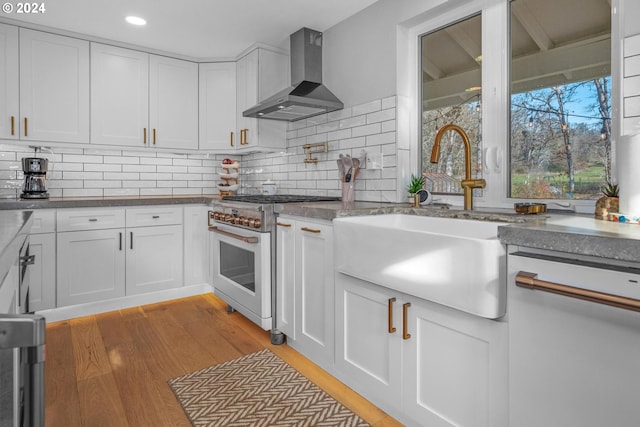 kitchen with white cabinets, light wood-type flooring, high end stainless steel range oven, and wall chimney exhaust hood