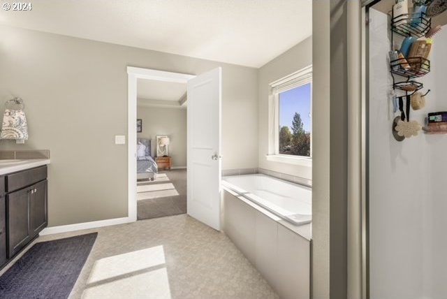 bathroom featuring tiled tub and vanity