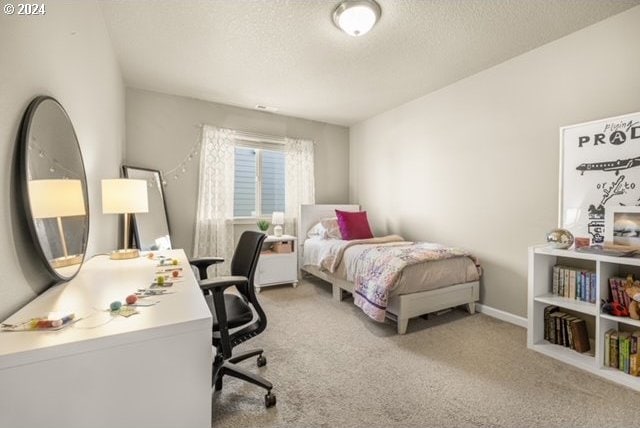 bedroom featuring light colored carpet and a textured ceiling