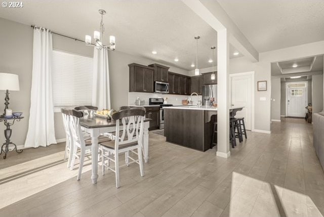 dining space with sink, an inviting chandelier, and light wood-type flooring