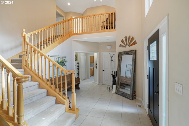 entryway with light tile patterned floors, a towering ceiling, and a healthy amount of sunlight