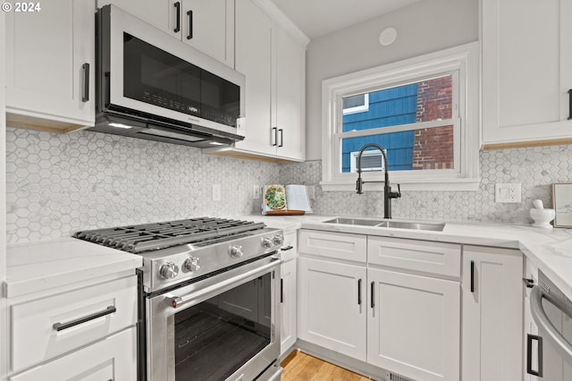 kitchen featuring appliances with stainless steel finishes, backsplash, white cabinetry, and sink