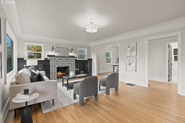 living room featuring hardwood / wood-style flooring, ornamental molding, and a tile fireplace