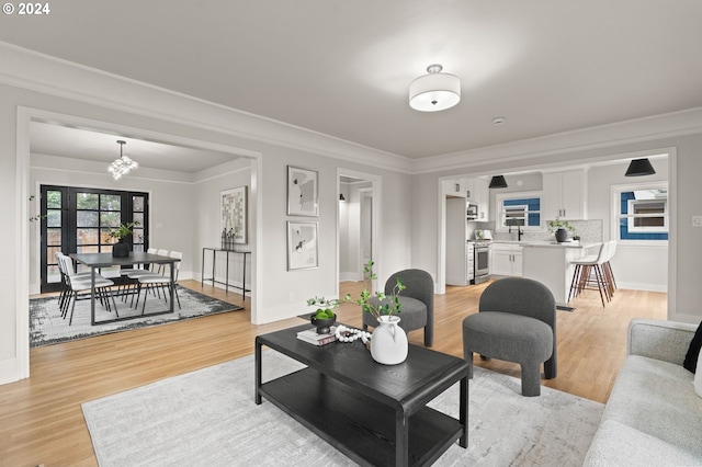 living room featuring light hardwood / wood-style floors, an inviting chandelier, and ornamental molding