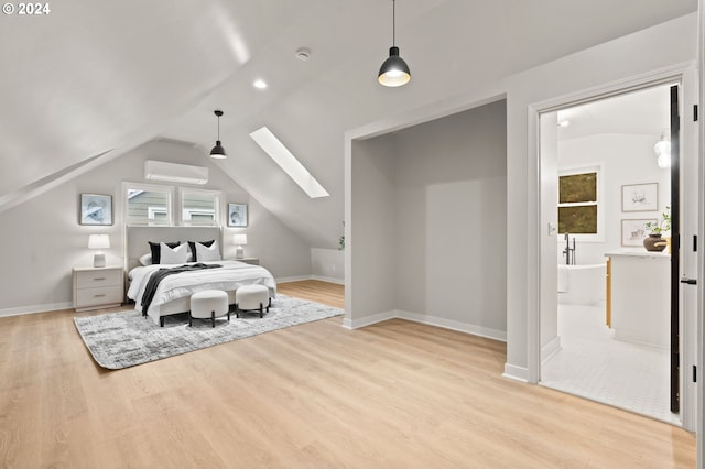 bedroom with connected bathroom, light hardwood / wood-style floors, a wall unit AC, and vaulted ceiling