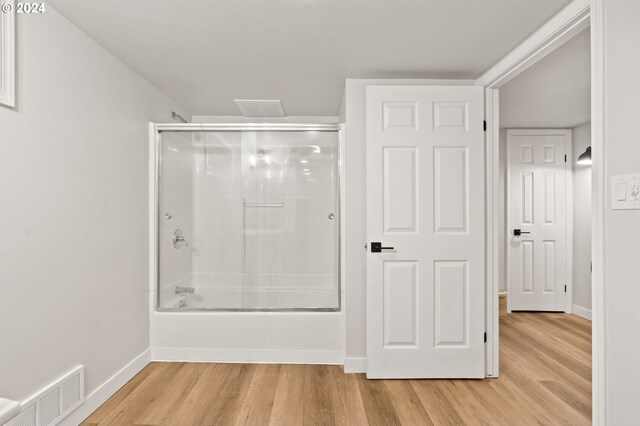 bathroom with hardwood / wood-style floors and enclosed tub / shower combo