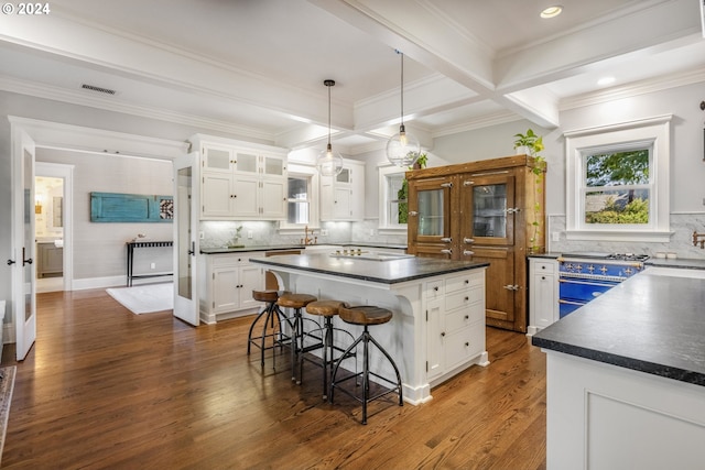 kitchen with dark countertops, visible vents, range with two ovens, and beam ceiling