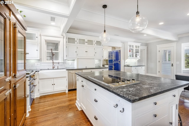 kitchen featuring a sink, light wood-style floors, premium appliances, and beamed ceiling