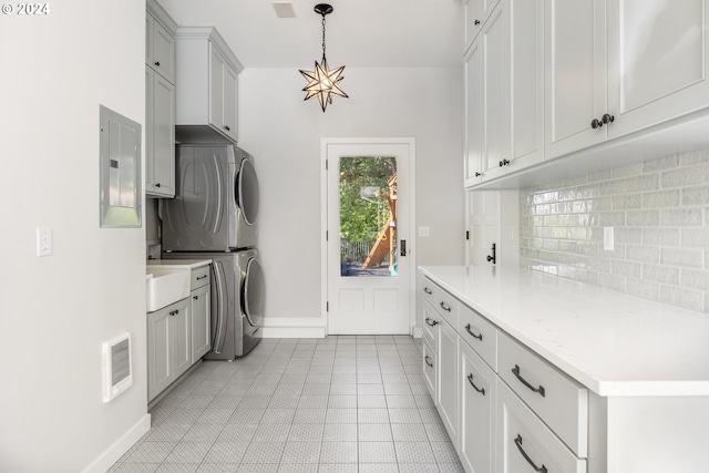 kitchen with stacked washer / drying machine, light countertops, visible vents, decorative backsplash, and electric panel