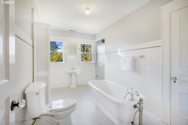 full bathroom with visible vents, toilet, a soaking tub, tile patterned floors, and tile walls