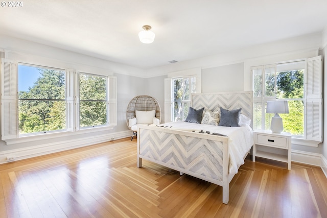 bedroom featuring wood finished floors, visible vents, and baseboards