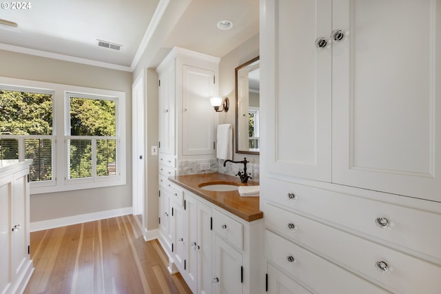 bathroom featuring crown molding, visible vents, vanity, wood finished floors, and baseboards