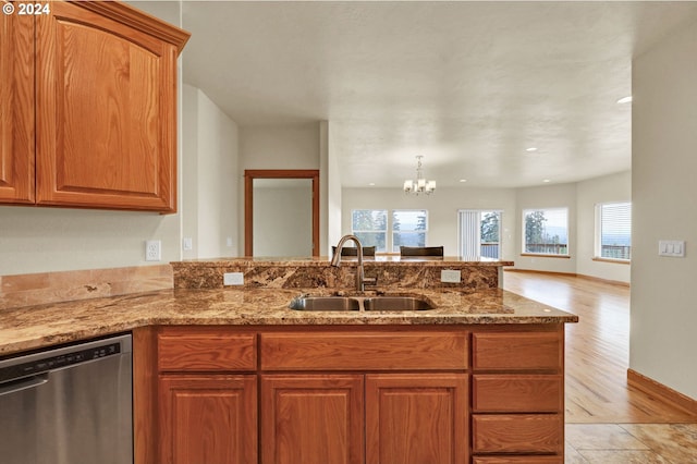 kitchen featuring light stone countertops, sink, an inviting chandelier, dishwasher, and light hardwood / wood-style floors