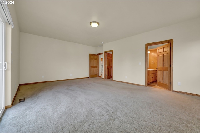 unfurnished bedroom featuring connected bathroom and light colored carpet