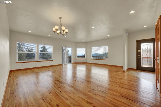 unfurnished living room featuring an inviting chandelier and light wood-type flooring