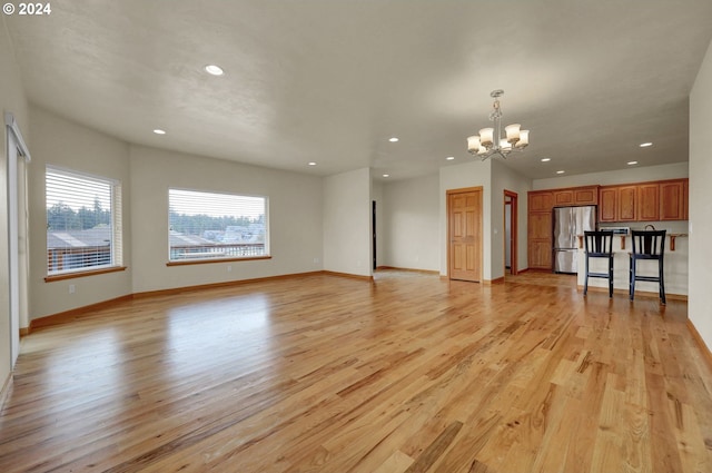 unfurnished living room with light hardwood / wood-style floors and an inviting chandelier