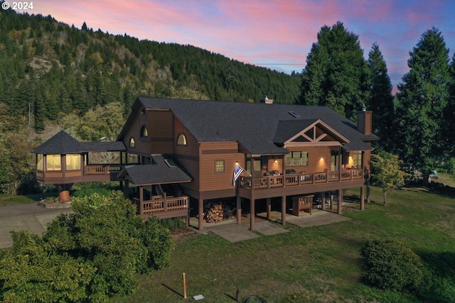 back house at dusk featuring a yard and a deck with mountain view