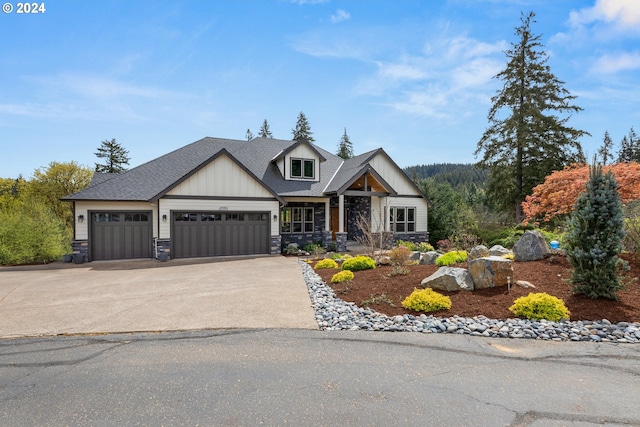 view of front of home with stone siding, roof with shingles, driveway, and an attached garage