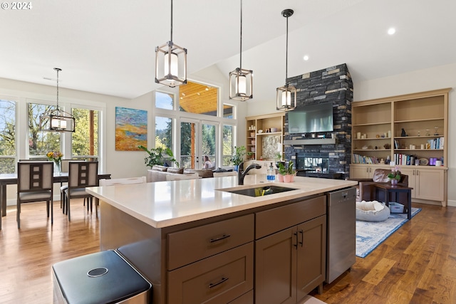 kitchen featuring a fireplace, light hardwood / wood-style floors, sink, and hanging light fixtures