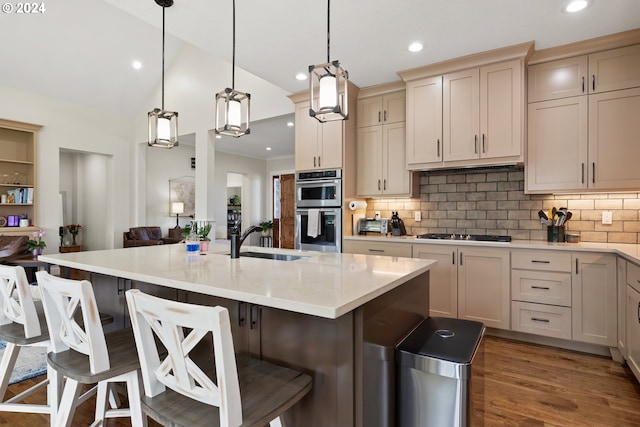 kitchen with backsplash, sink, double oven, wood-type flooring, and hanging light fixtures