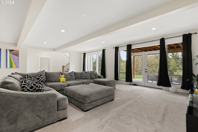 living room featuring beamed ceiling, plenty of natural light, and light carpet