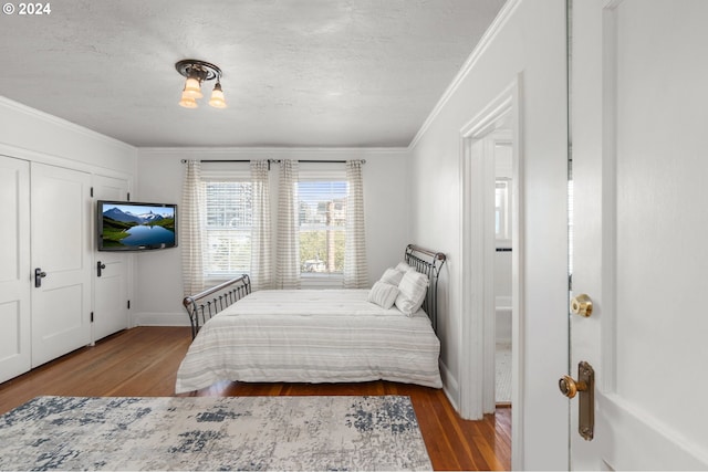 bedroom with wood-type flooring, ornamental molding, and a textured ceiling