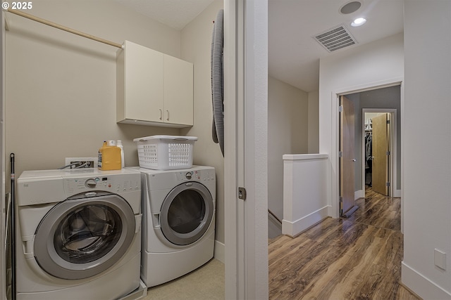 clothes washing area featuring dark hardwood / wood-style flooring, cabinets, and independent washer and dryer